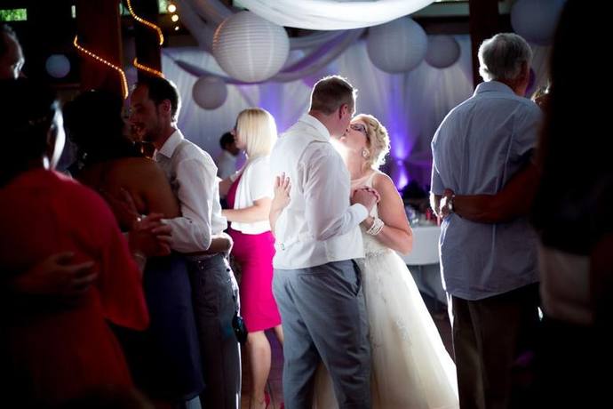 Couple dancing closely during a warmly lit wedding reception with guests in the background