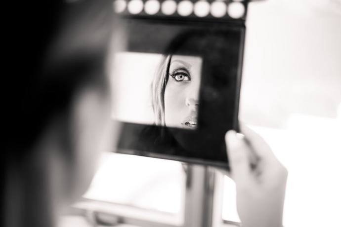 Black-and-white creative bridal portrait reflected in a makeup mirror, framing one eye and part of her face
