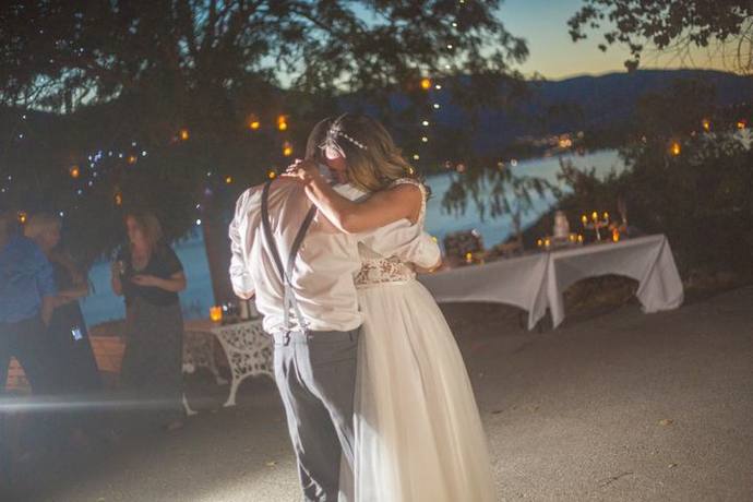 Bride and groom embracing during an outdoor evening celebration with lake views and glowing lights