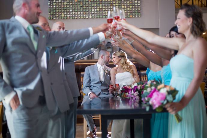 Wedding party raising glasses in a celebratory toast around the newlyweds at their reception