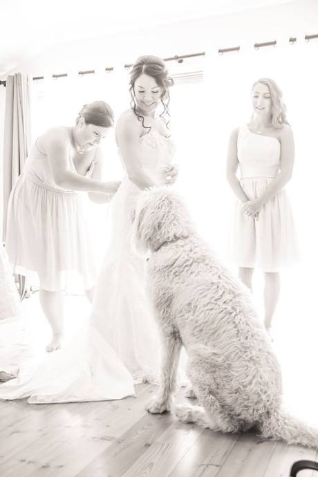 Bride smiling during wedding preparations as her fluffy dog sits beside her