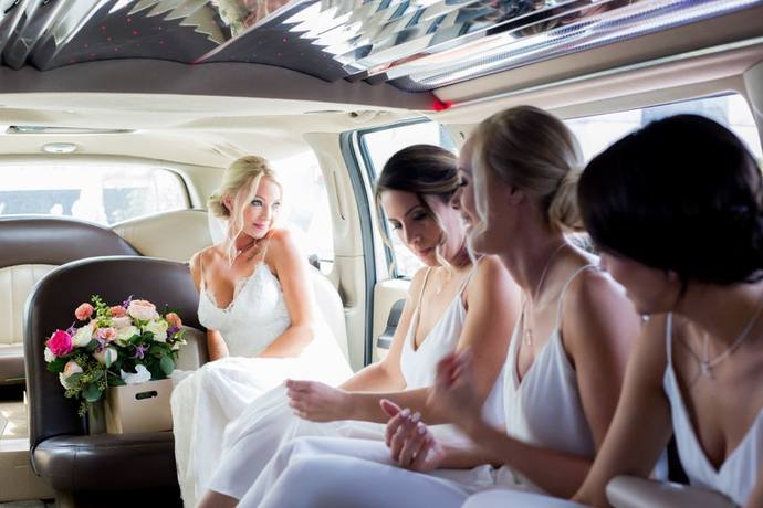 Bride and bridesmaids smiling together inside a limousine before a Penticton wedding