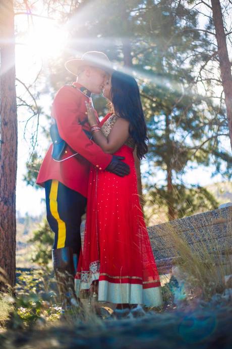 Wedding couple sharing a quiet embrace outdoors, with one partner wearing a red dress uniform