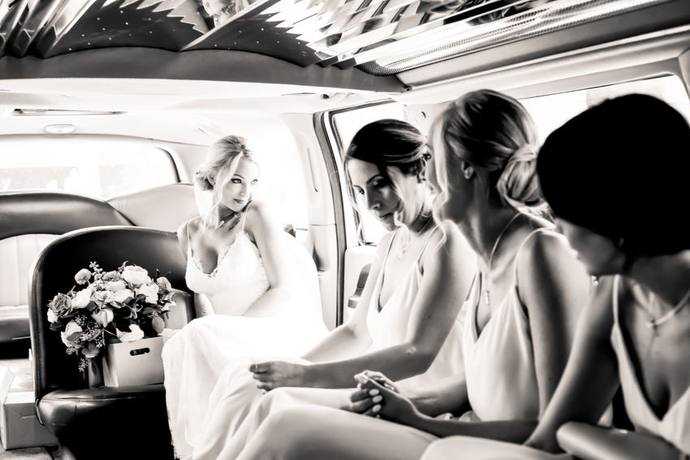 Black-and-white photograph of a bride and bridesmaids sitting together in a limousine